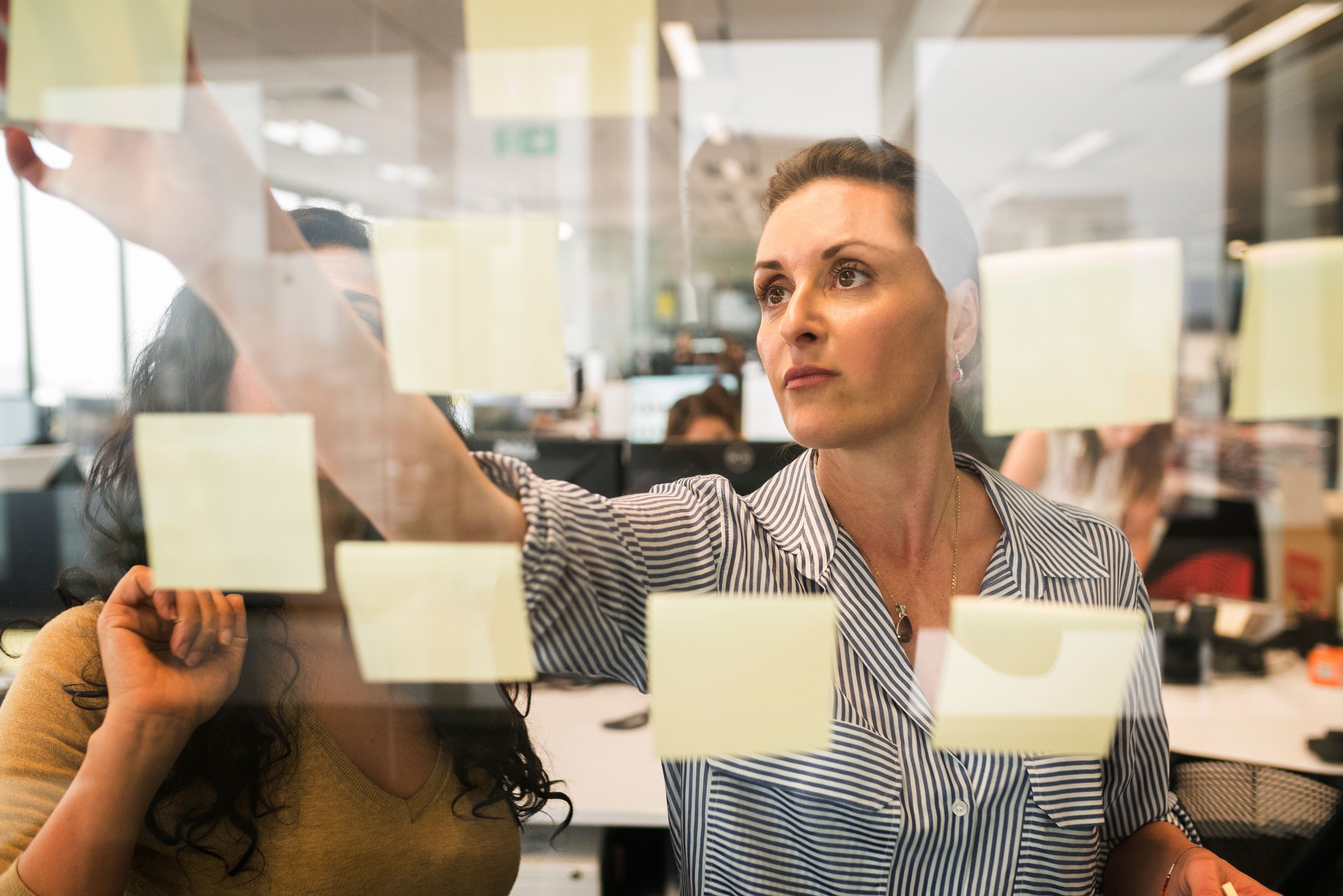 A participant arranging ideas on a glass wall covered in sticky notes